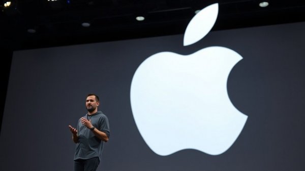 Speaker on stage with Apple logo during keynote presentation.