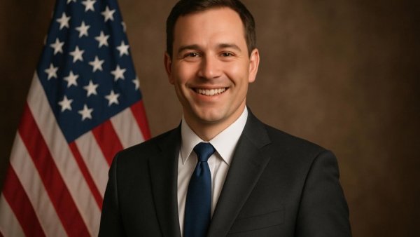 Professional man in a suit smiling in front of U.S. flag, related to data center siting ordinance.