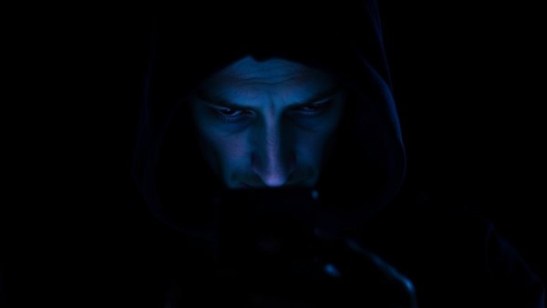 Mysterious person in hoodie checking phone, AIIMS job scams concept.