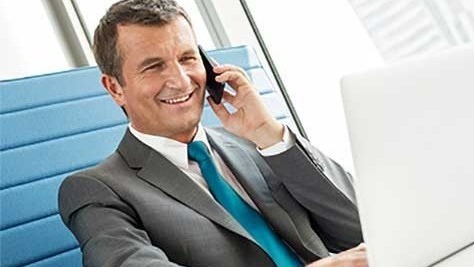 Businessman at desk on mobile phone and computer