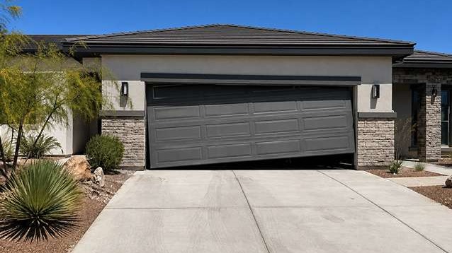 Las Vegas home with crooked garage door hanging unevenly in front of a clean driveway and desert landscaping