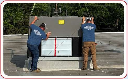 Two Anderson Heating and Cooling technicians installing commercial HVAC on rooftop of building Central Kentucky