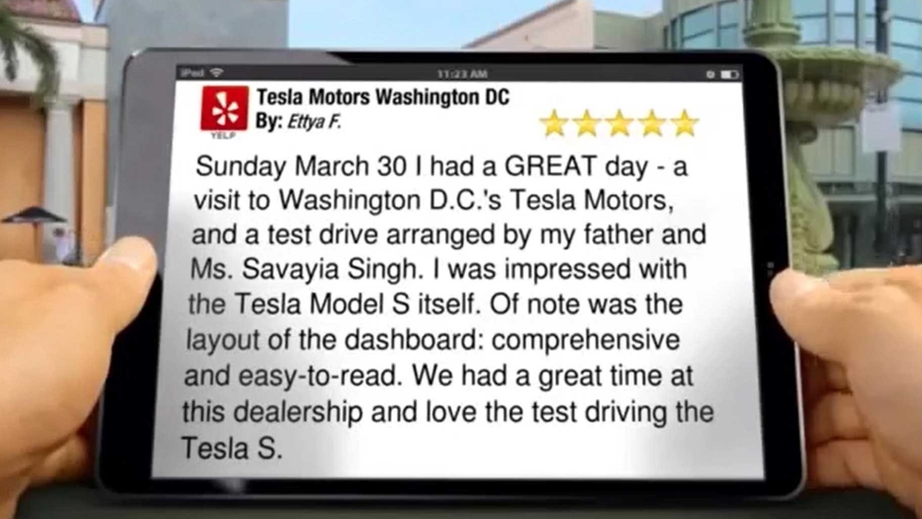 hands holding an iPad viewing a 5 star review for Tesla Motors.