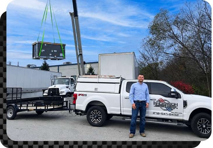 Anderson Heating and Cooling lifting a commercial HVAC unit onto a building, with Jake Anderson standing in front of his truck in Central Kentucky