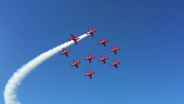 Stunt planes at Dubai Airshow performing synchronized aerial maneuvers with smoke trails.