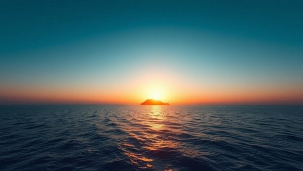 Serene ocean sunrise with sun over island reflecting on the water.