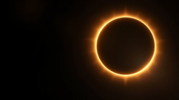 Dramatic annular solar eclipse with glowing ring in cosmic black backdrop.