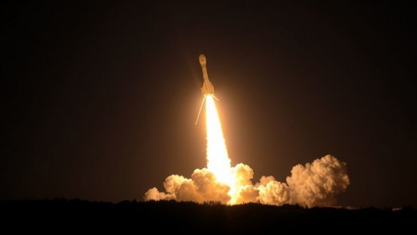 Rocket launch showcasing space innovation with fiery exhaust at night.