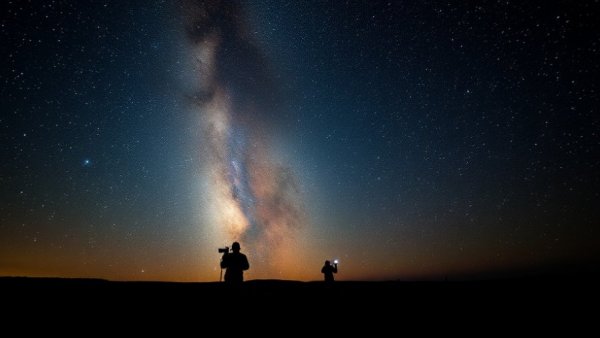 Stargazer photographing night sky with telescopes under Pleiades stars.