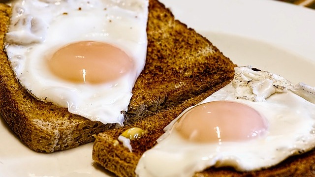 Close-up of hands cracking an egg, highlighting nutritional value of eggs for heart health.