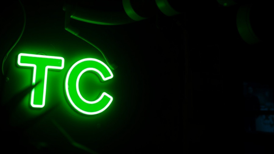 Bright green TC neon sign, dark room setting.