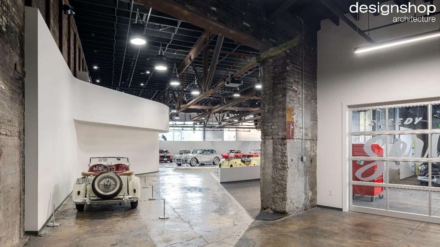 Edge Motor Museum gallery in a restored Memphis warehouse with exposed brick, steel trusses and classic cars on display, designed by designshop architecture