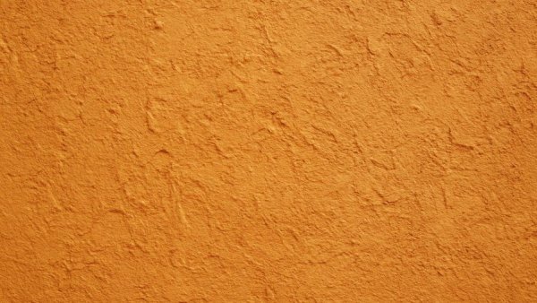 Inexpensive textured walls with orange rough surface close-up.