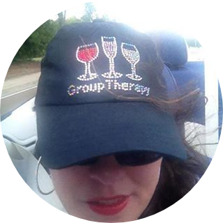 Melanie T Facebook Profile Image wearing a hat that says group therapy with wine glasses