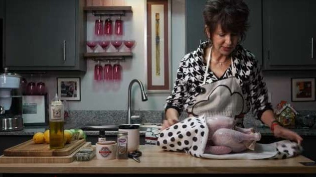 Surprised cook watches burning turkey in a cluttered kitchen setting.