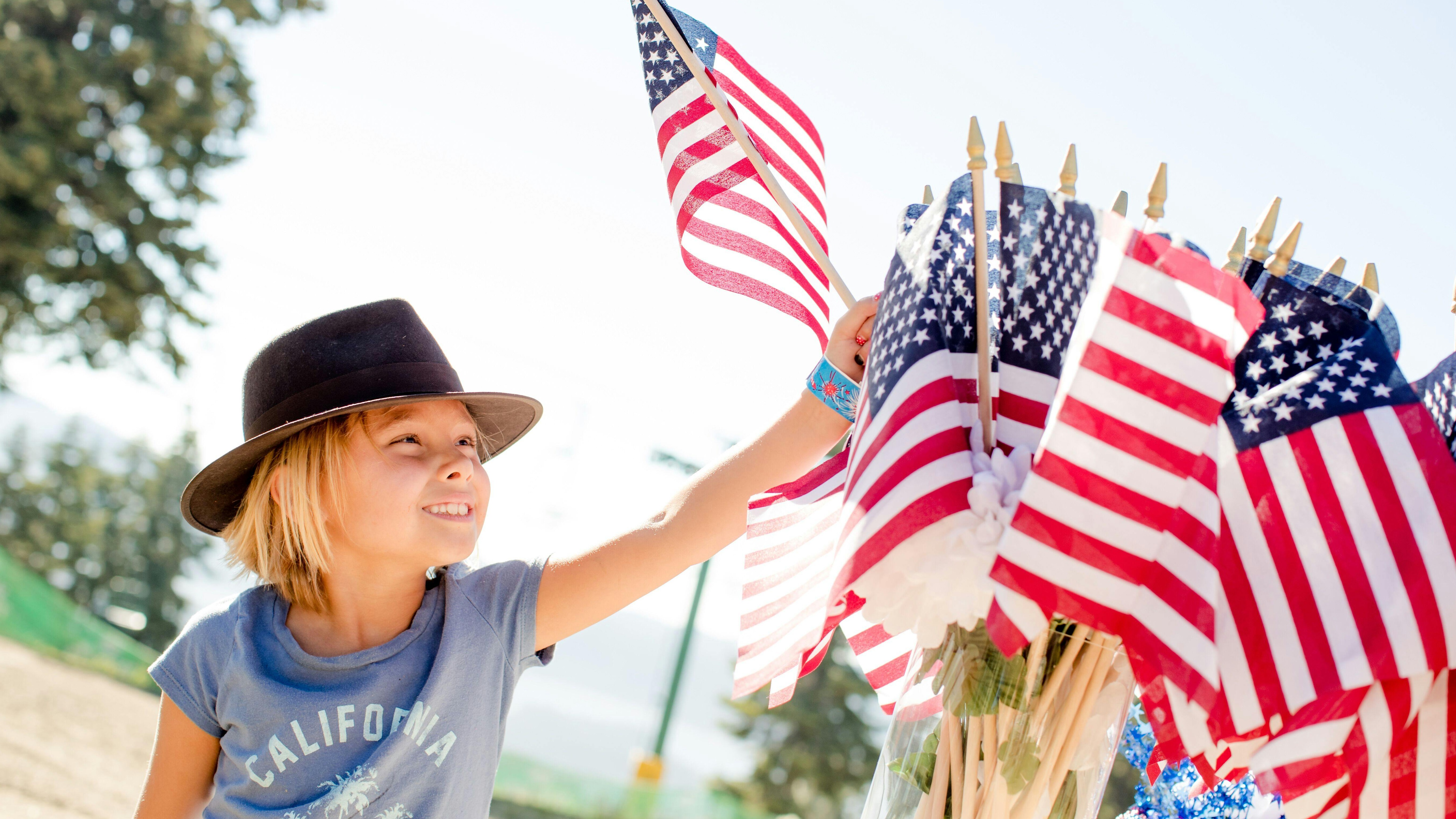 Smiling TV hosts with scenic view background promoting 4th of July safety tips.