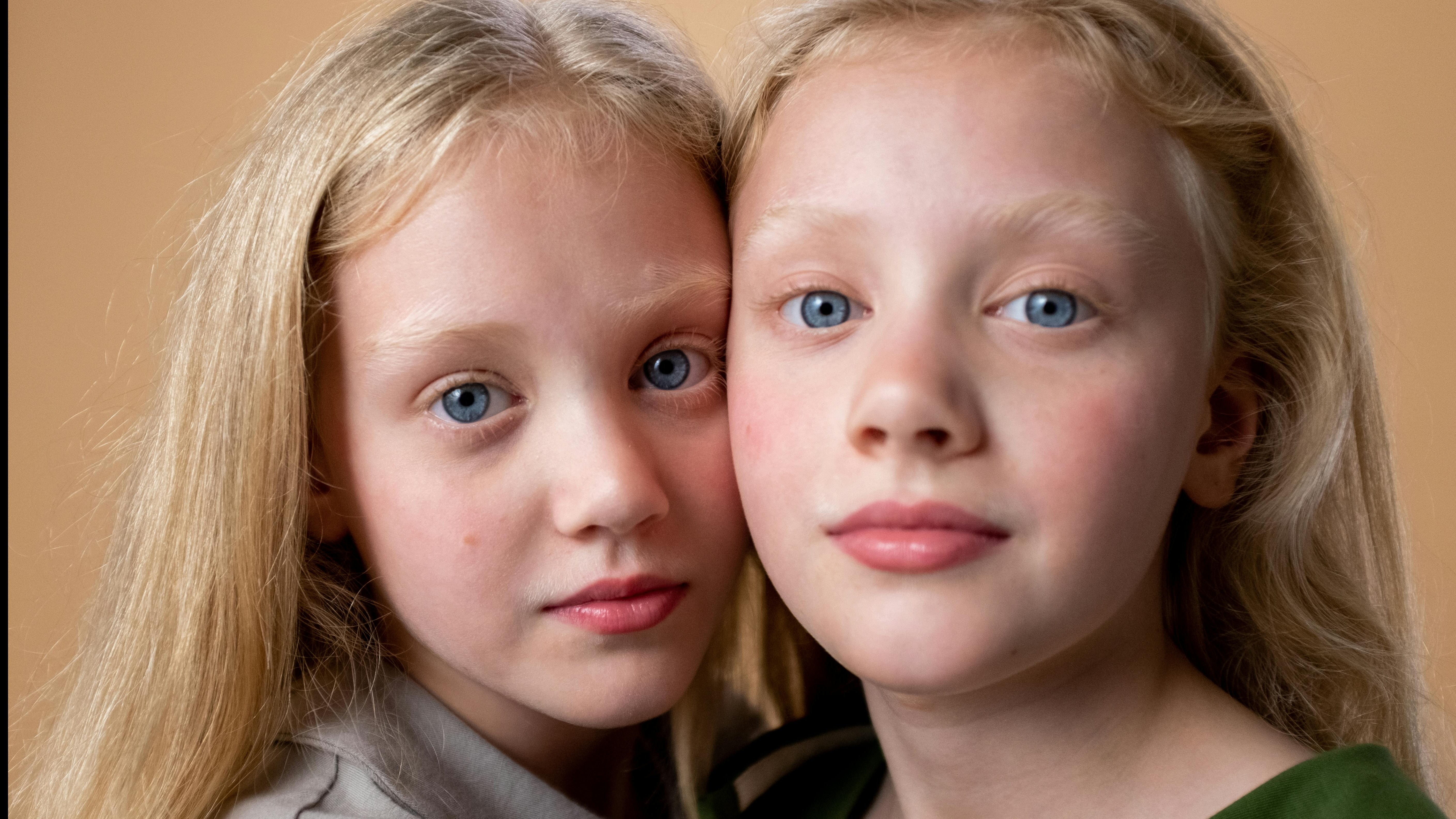 Identical twin sisters smiling for National Twin Day celebration.