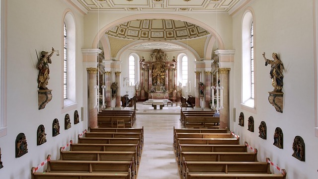 Young woman in a red jacket explaining on a busy street at night.
