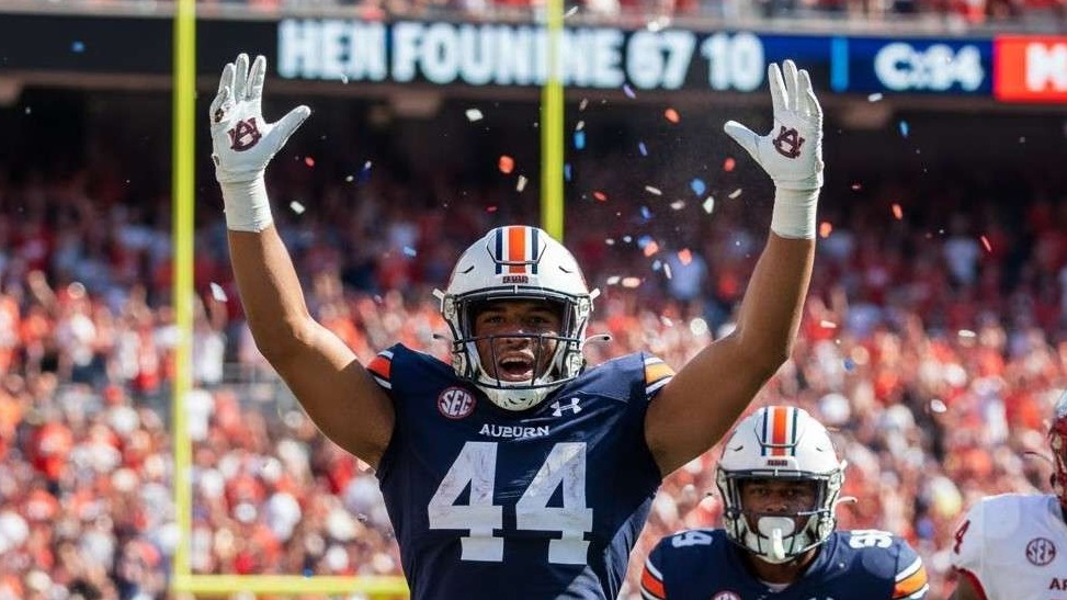 Bald man in sports hoodie at a stadium, Arkansas Razorbacks atmosphere.