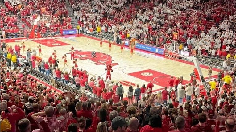 Arkansas Razorbacks fans cheering in a packed basketball arena.