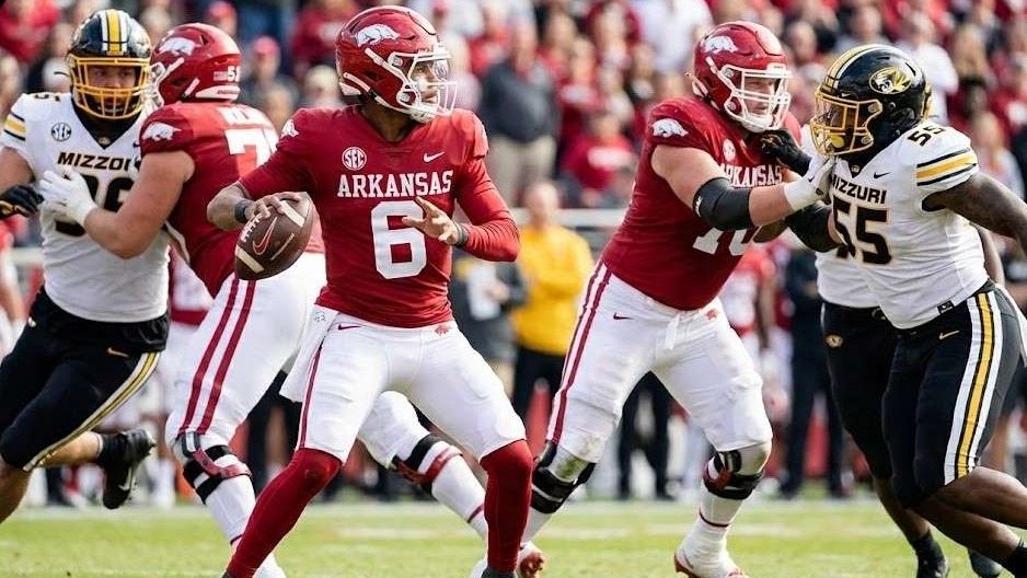Arkansas Razorbacks athletes at a press conference with logo backdrop.