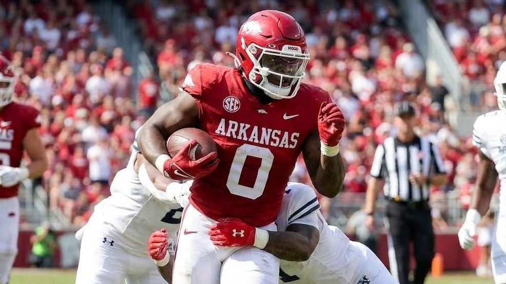 Bald man speaking into a microphone in a studio setting.