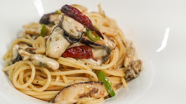 Young man discussing Zelli Pasta new location indoors, casual setting.