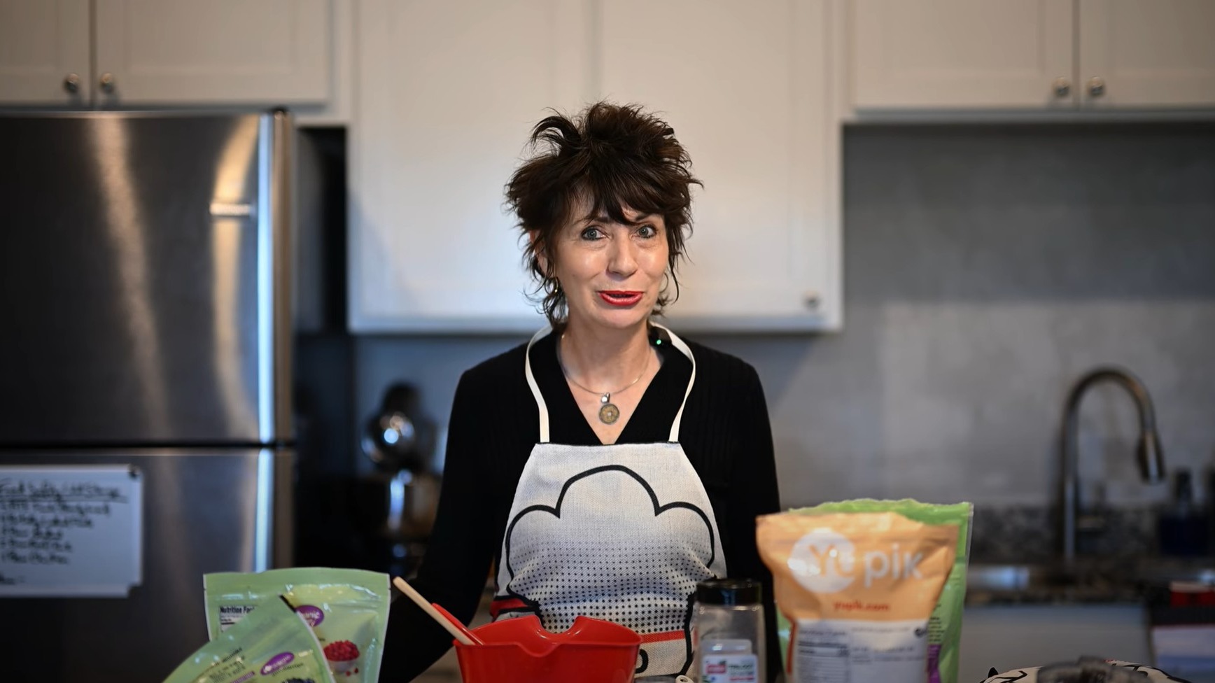 Smiling woman in kitchen with apron and knife, cooking enthusiast.