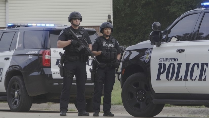 Police at Siloam Springs arrests scene, parking lot tense situation.