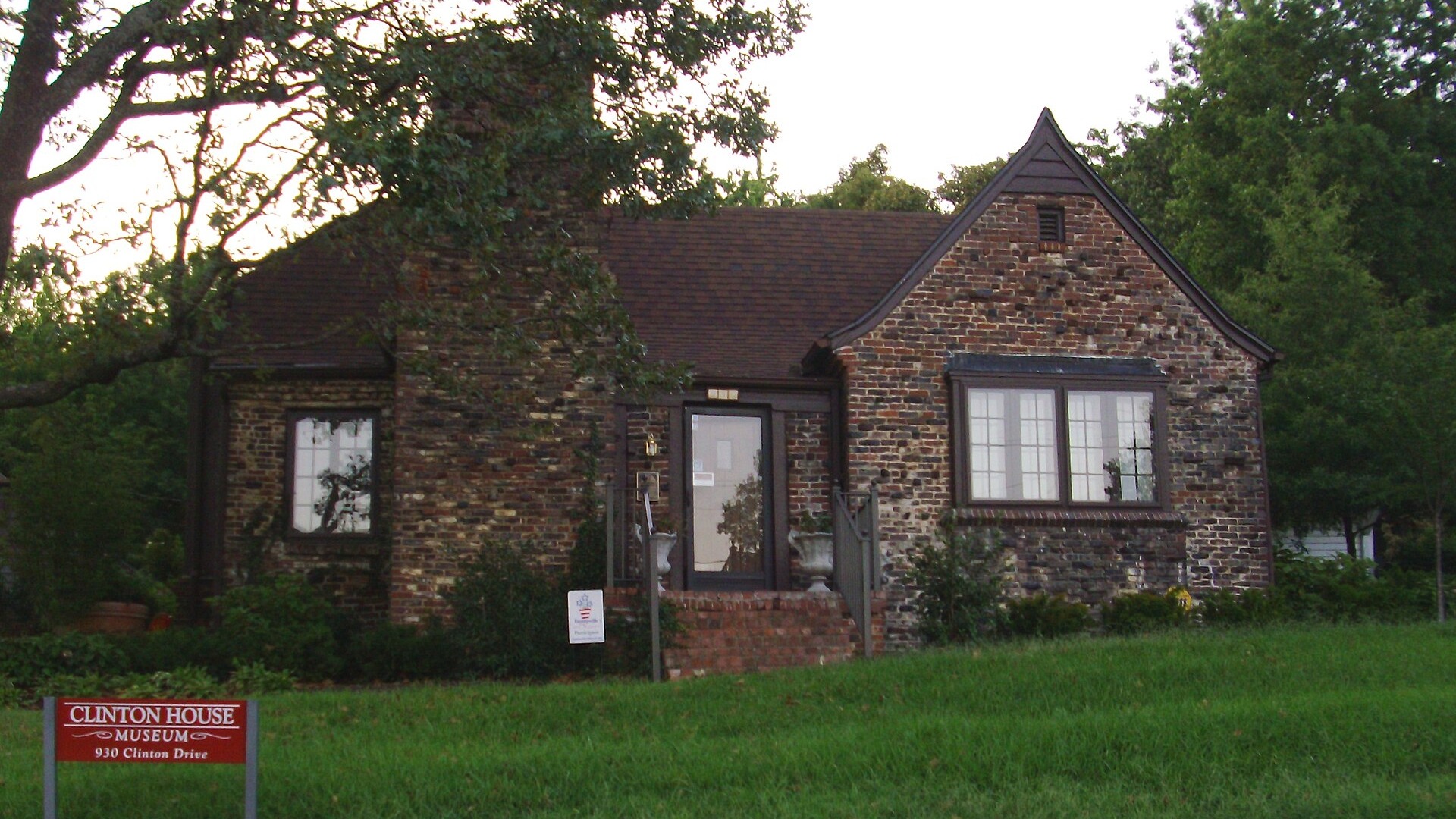 Clinton House Museum, brick cottage with lush greenery.