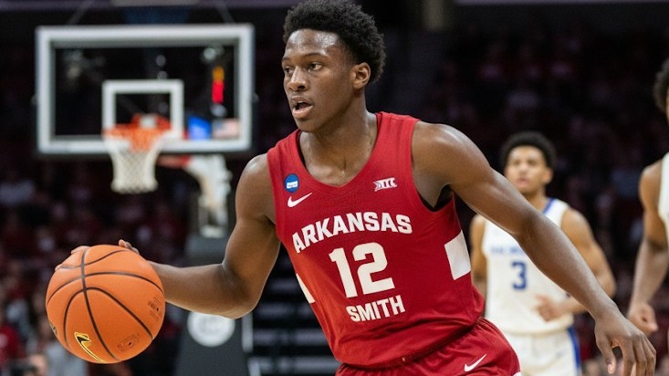 Arkansas basketball commitment featuring young athlete and mentor smiling in front of award banner.