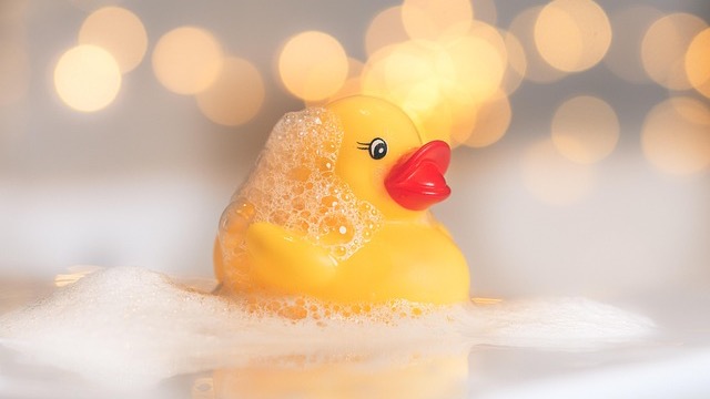 Three rubber ducks celebrating National Rubber Ducky Day in foamy water.