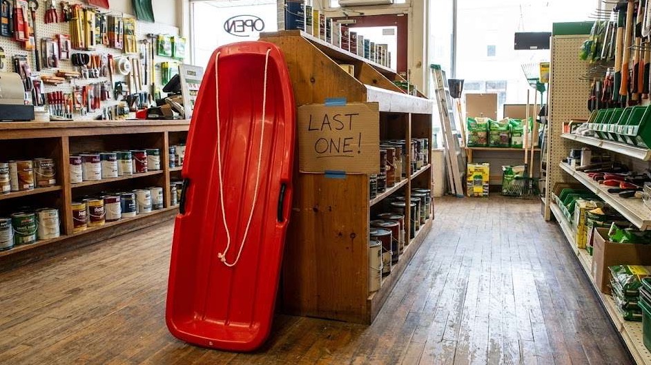 Friendly woman in hardware store, vibrant shelves, Fayetteville.