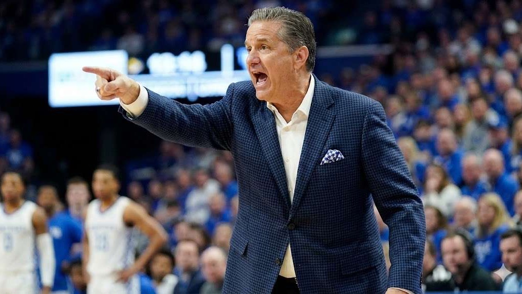 Energetic man speaking at indoor event, Arkansas Razorbacks.