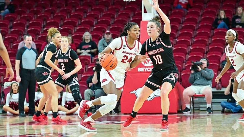 Arkansas women's basketball player discussing with coach during game.