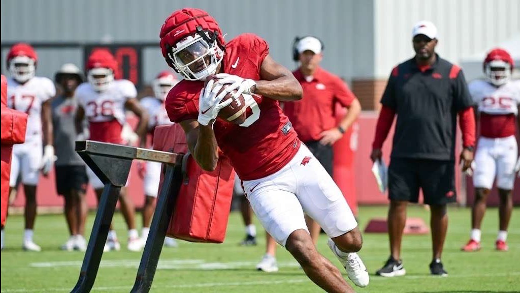 Focused Razorbacks player returning, sporting red jersey.