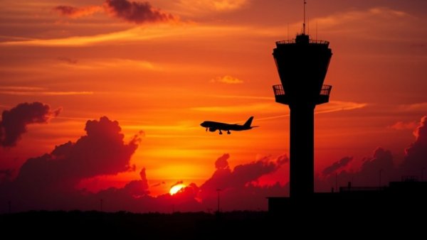 DFW Airport control tower and airplane at sunset, holiday travel.