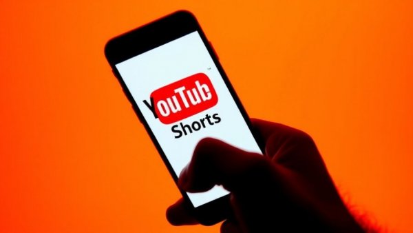YouTube Shorts logo on smartphone against thematic background