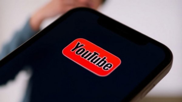 YouTube logo on phone screen with blurred background, representing AI creation tools on YouTube.