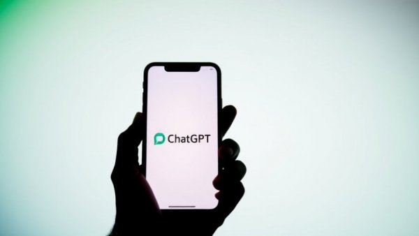 Silhouette with smartphone showing ChatGPT logo, OpenAI background.