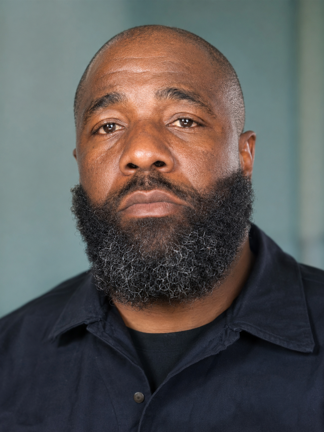 Close-up of a man with a neutral expression indoors.