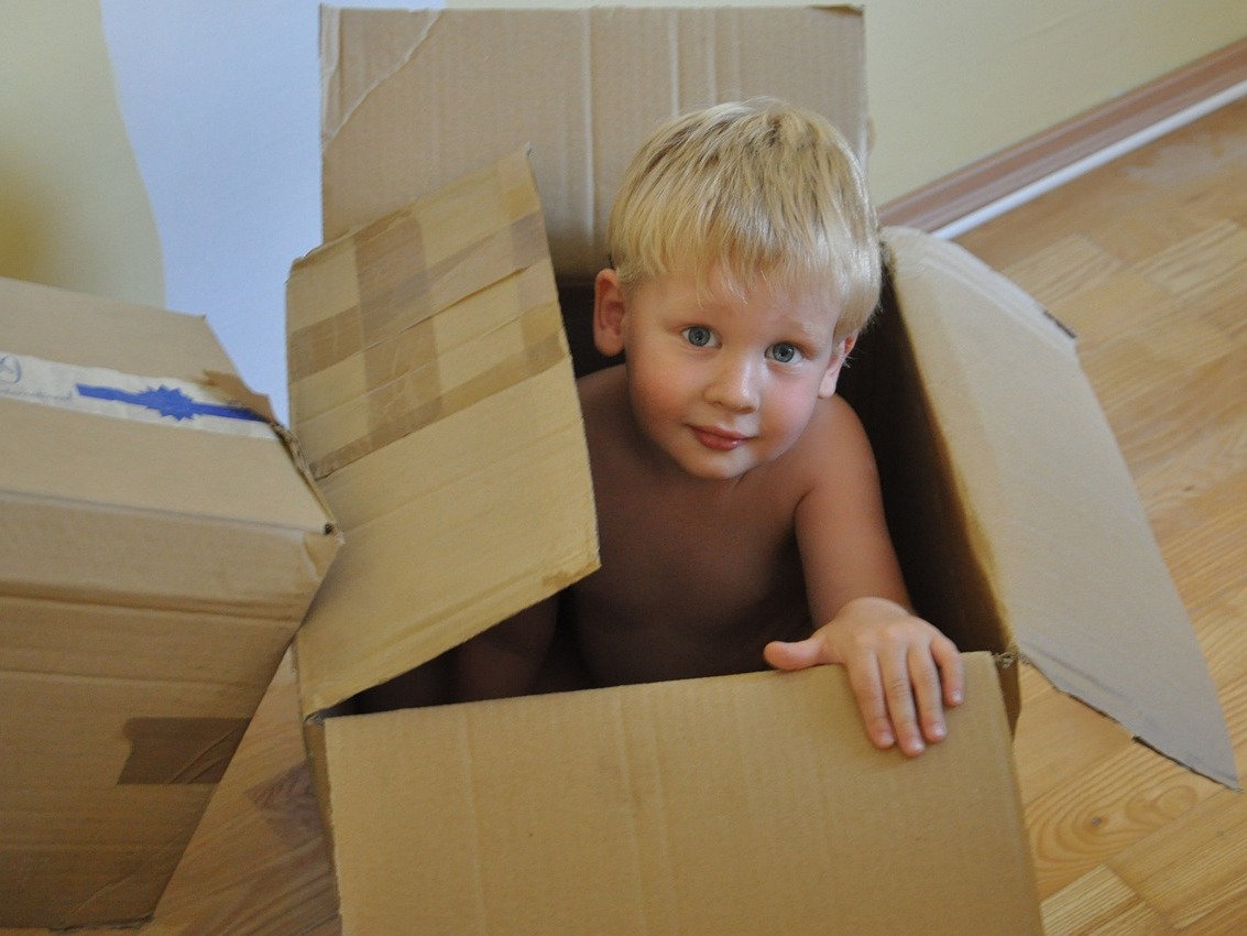 moving with children - photograph of little boy in a cardboard moving box