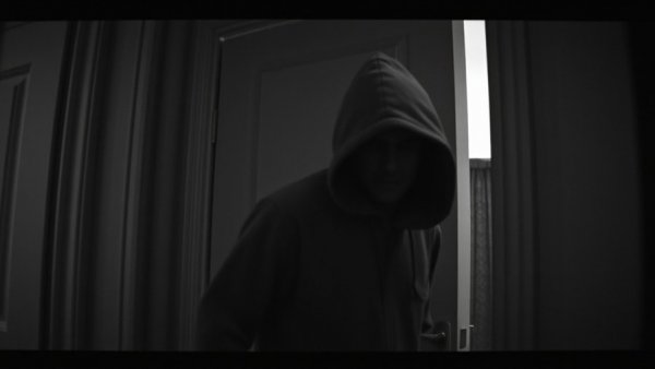 Grainy surveillance image of a masked burglar in a doorway, related to a serial burglar in Philadelphia.