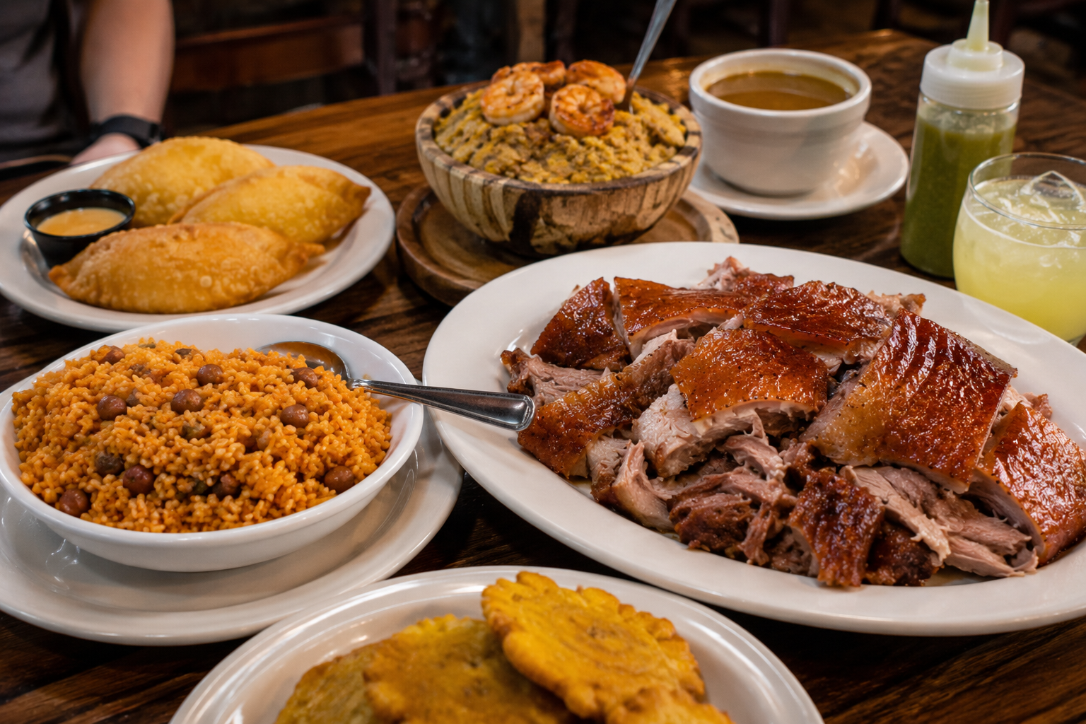 Puerto Rican dishes including pernil, arroz con gandules, mofongo, pastelillos, and tostones served on a restaurant table in Western New York