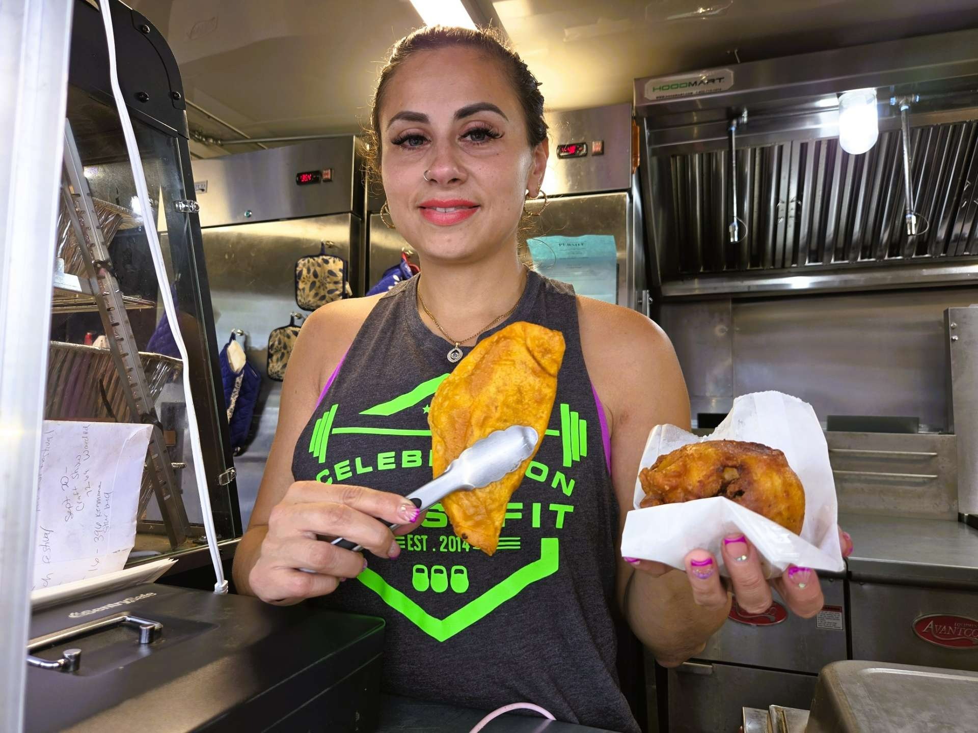 Grandmother of the El Gran Coqui Catering family standing beside her image on the Puerto Rican food trailer