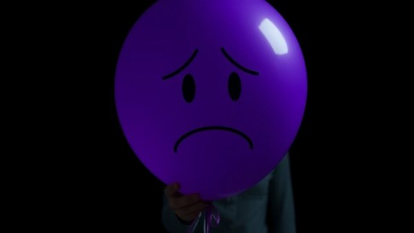 Sad face balloon symbolizes mental health theme.