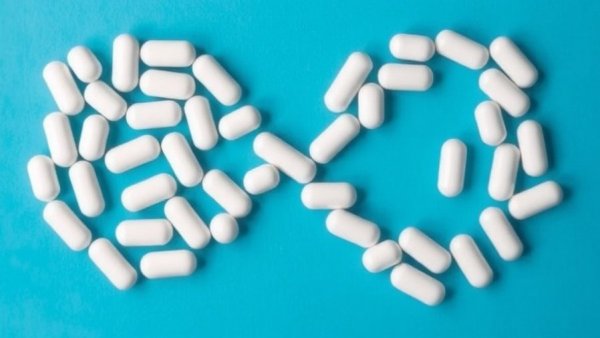 White pills forming infinity on blue background, GLP-1 weight loss.