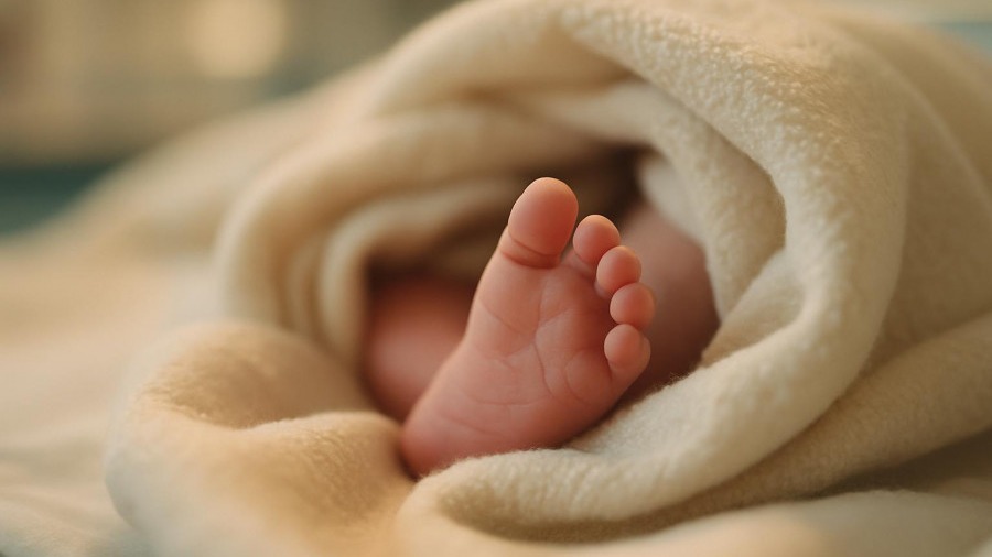 Close-up of a newborn's foot in a warm hospital setting, highlighting newborn screening programs.