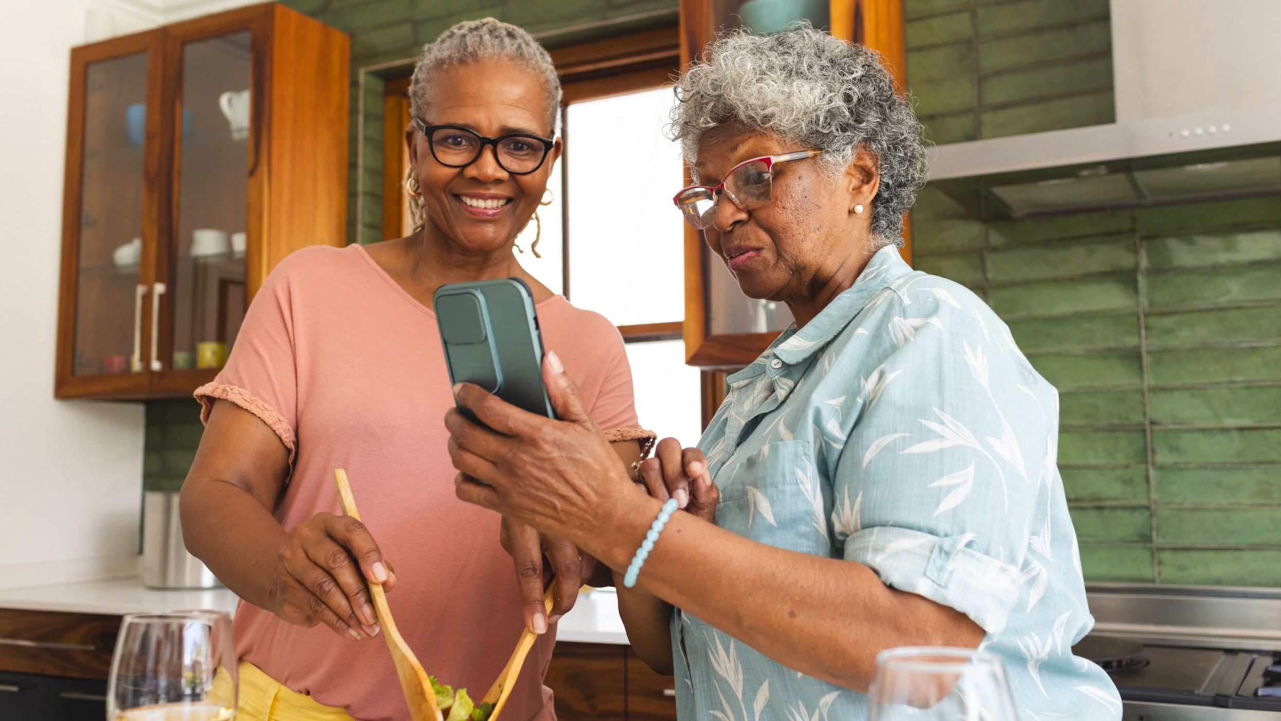 Female home care provider with her client helping her make a salad