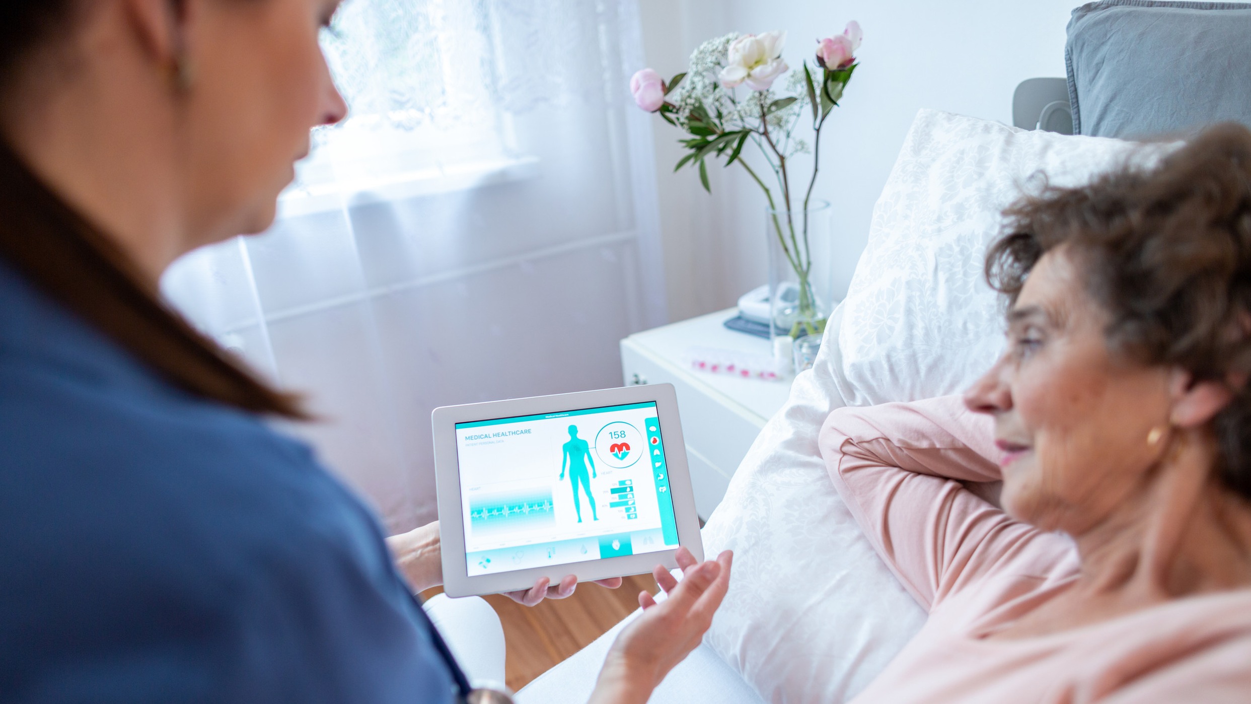 Remote patient monitoring compliance: Elderly man using a blood pressure monitor at home.